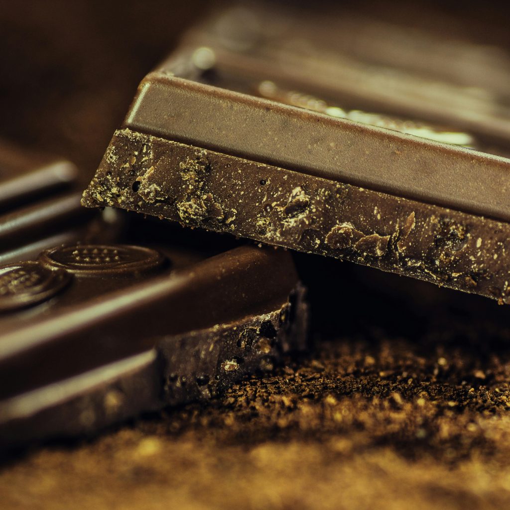 Macro shot of rich dark chocolate bars sprinkled with cocoa powder, highlighting texture and indulgence.
