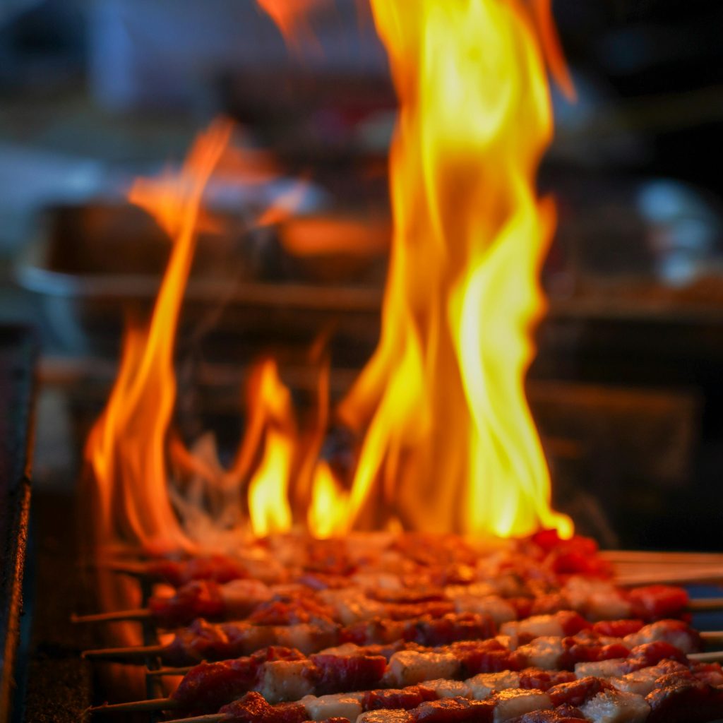 Juicy meat skewers being grilled over an open flame, perfect for BBQ lovers.